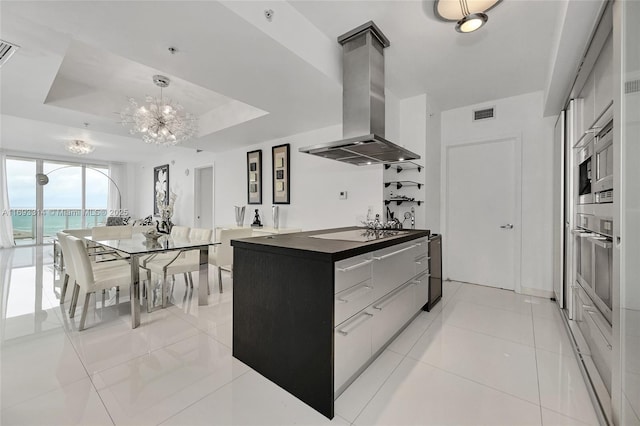 kitchen with extractor fan, a raised ceiling, light tile patterned floors, a water view, and oven