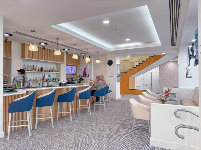 bar with a raised ceiling, carpet, and decorative light fixtures