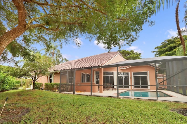 rear view of house featuring a lawn, glass enclosure, and a patio