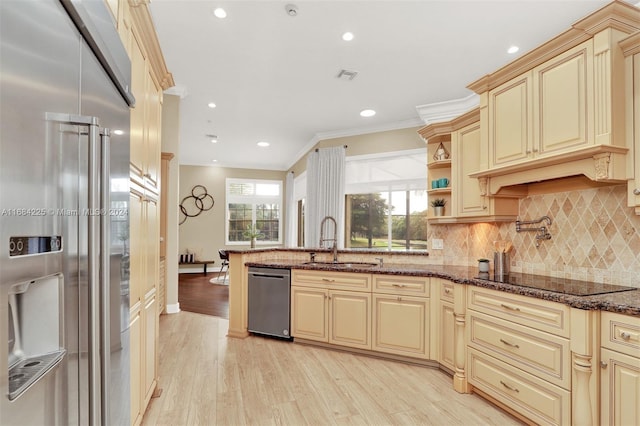 kitchen featuring light hardwood / wood-style flooring, ornamental molding, sink, dark stone counters, and stainless steel appliances