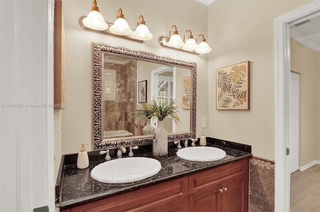 bathroom featuring vanity, ornamental molding, a tub to relax in, and wood-type flooring