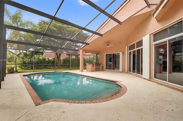 view of pool with glass enclosure, ceiling fan, exterior kitchen, and a patio