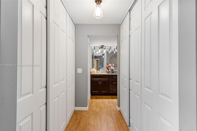 corridor featuring sink, light hardwood / wood-style floors, and a textured ceiling