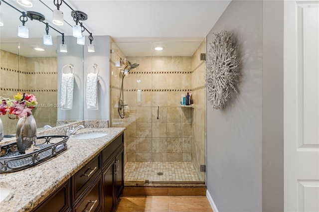 bathroom with walk in shower, vanity, and hardwood / wood-style flooring