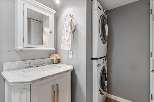 clothes washing area with stacked washer / drying machine and sink