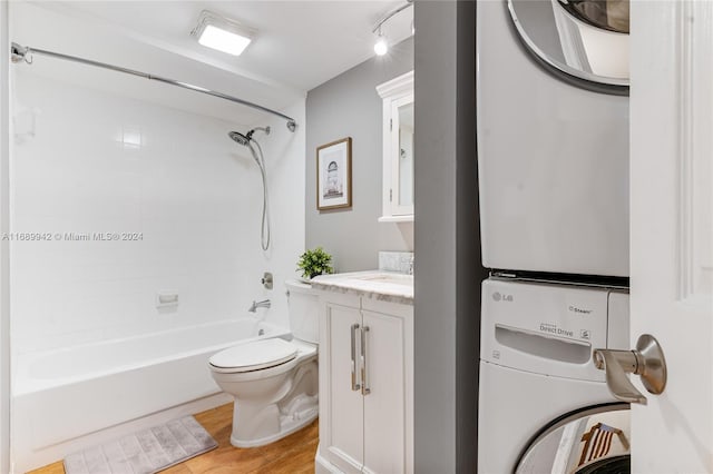 full bathroom featuring hardwood / wood-style floors, vanity, toilet, tiled shower / bath, and stacked washer / dryer