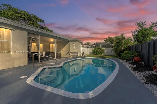 pool at dusk with a patio area