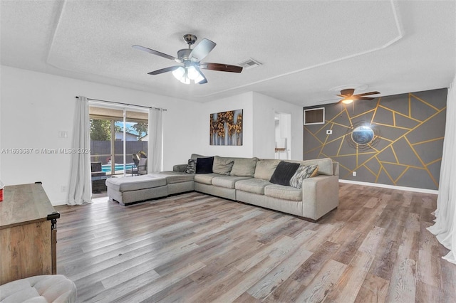 living room with ceiling fan, hardwood / wood-style flooring, and a textured ceiling