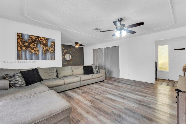 living room with ceiling fan, a textured ceiling, and hardwood / wood-style flooring