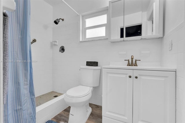 bathroom featuring tiled shower, wood-type flooring, toilet, and tile walls