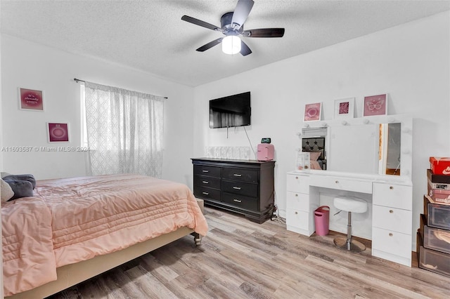 bedroom with a textured ceiling, light wood-type flooring, and ceiling fan