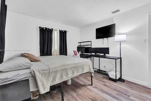 bedroom with hardwood / wood-style floors and a textured ceiling