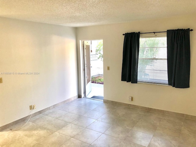 tiled empty room featuring a textured ceiling