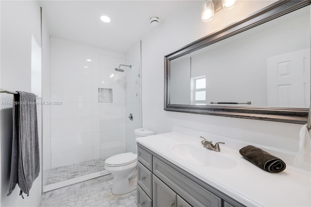 bathroom with tiled shower, vanity, and toilet