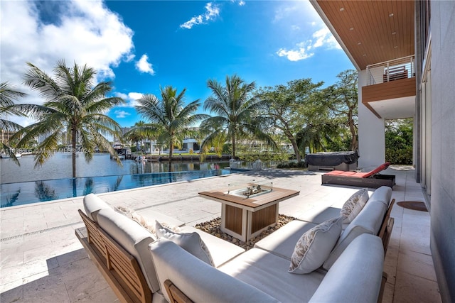 view of patio featuring a water view, an outdoor living space with a fire pit, and a hot tub