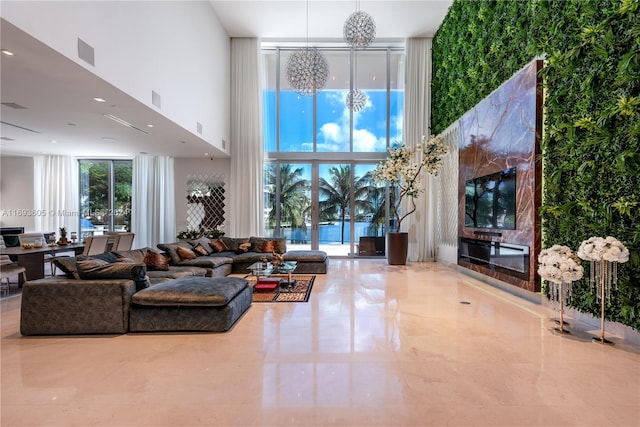 living room with a chandelier, a healthy amount of sunlight, a high ceiling, and a wall of windows