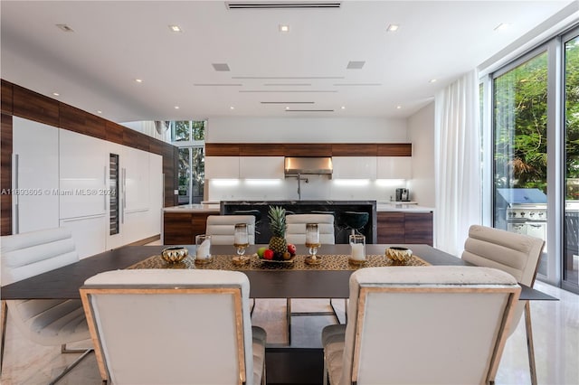 kitchen with a breakfast bar, a kitchen island, a wall of windows, and wall chimney range hood