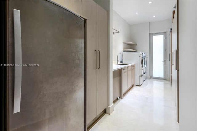 laundry room with washing machine and clothes dryer, sink, and cabinets