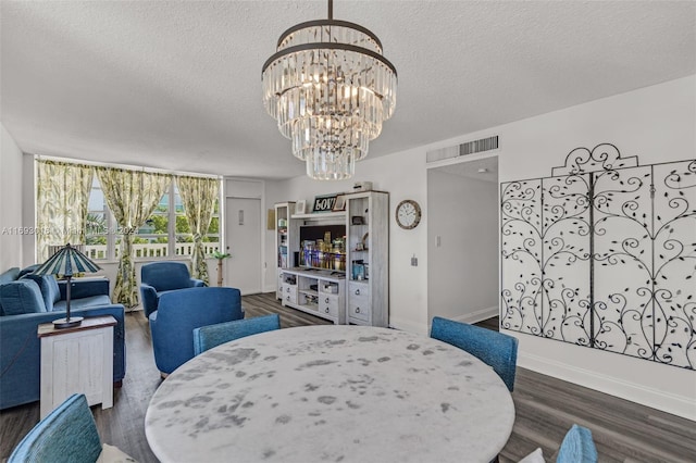 dining area with a chandelier, dark wood-type flooring, and a textured ceiling