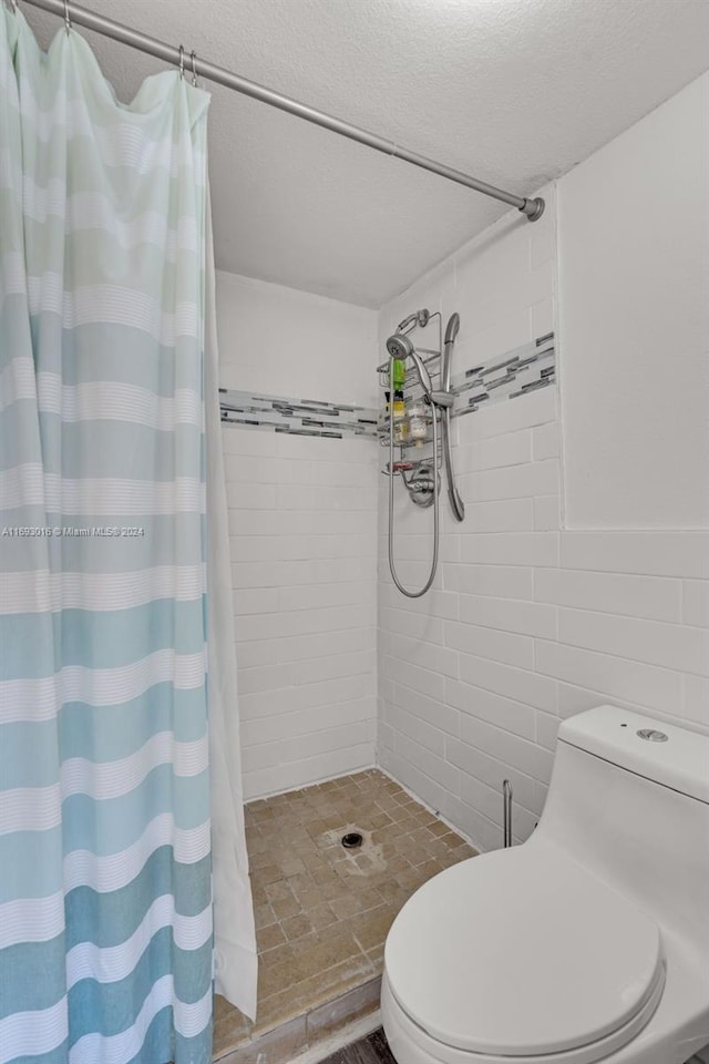 bathroom featuring a shower with curtain, tile walls, a textured ceiling, and toilet