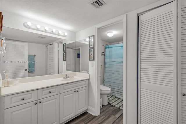 bathroom featuring vanity, hardwood / wood-style flooring, toilet, a textured ceiling, and curtained shower