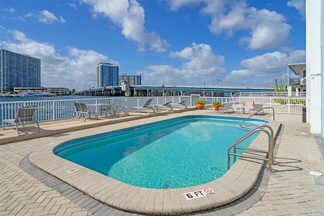 view of swimming pool with a water view and a patio area