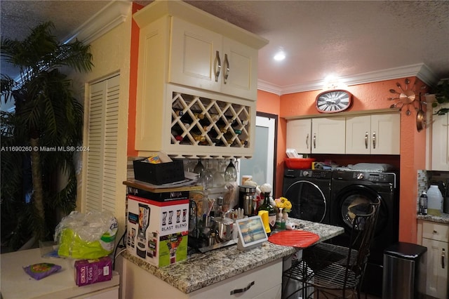 kitchen featuring white cabinets, independent washer and dryer, light stone counters, and crown molding