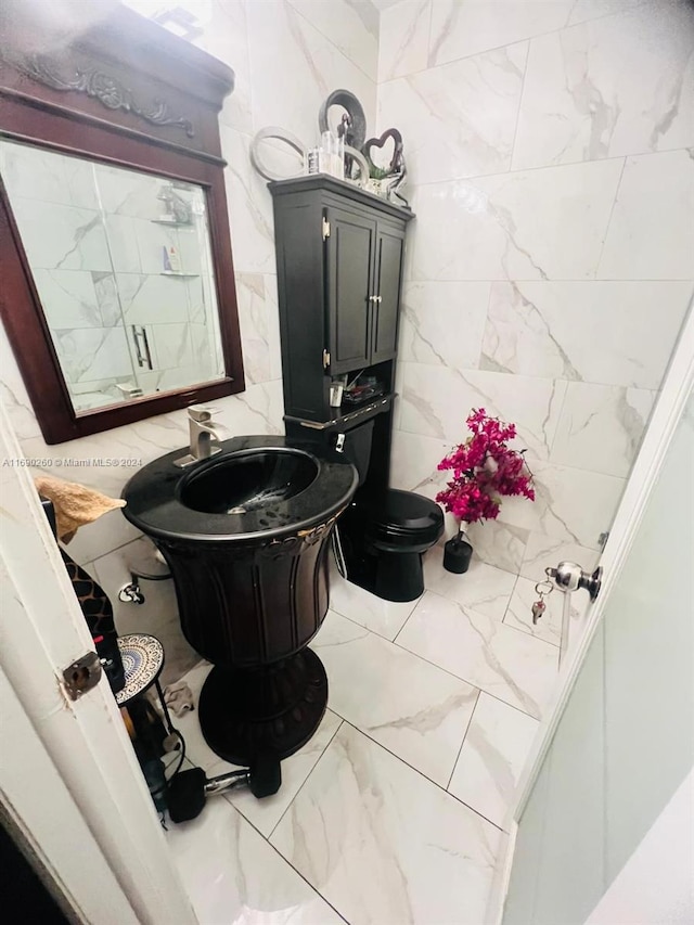 bathroom with vanity, toilet, and tile walls