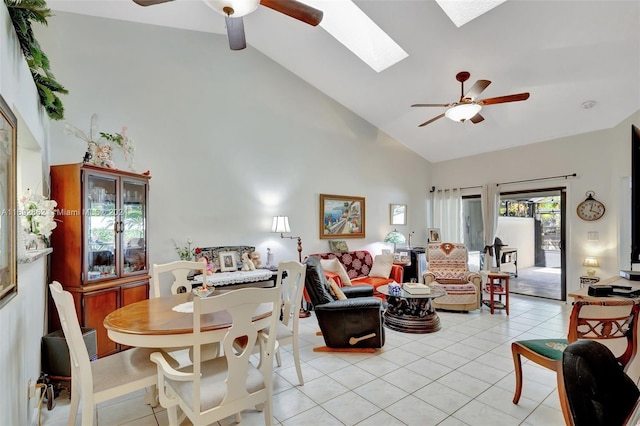 tiled living room with ceiling fan, high vaulted ceiling, and a skylight