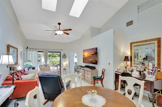 tiled dining room with ceiling fan and vaulted ceiling with skylight