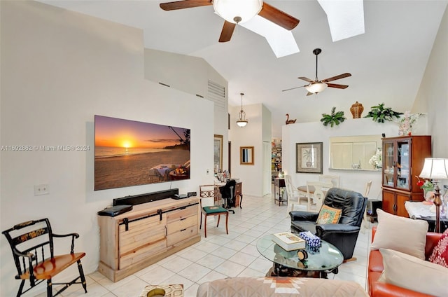 living room with ceiling fan, lofted ceiling with skylight, and light tile patterned flooring