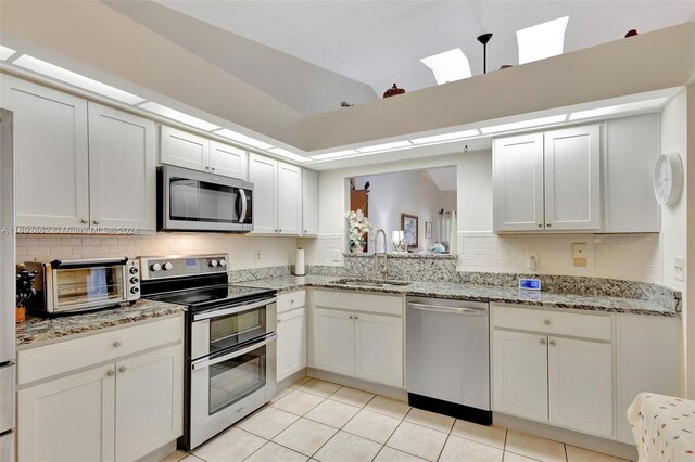 kitchen featuring light tile patterned flooring, appliances with stainless steel finishes, white cabinets, and sink