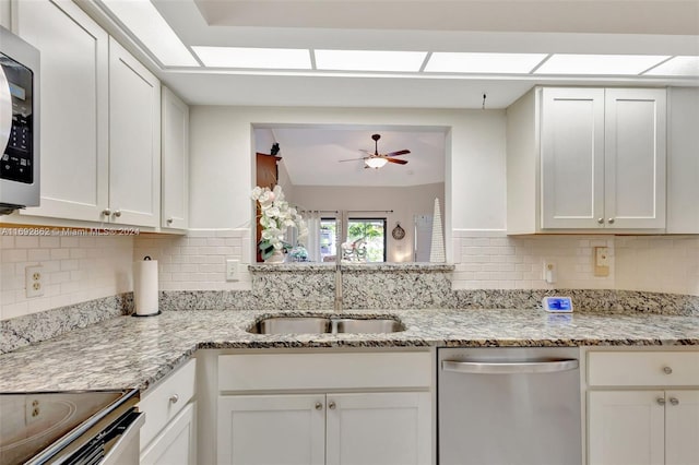 kitchen featuring light stone countertops, white cabinetry, stainless steel dishwasher, and sink