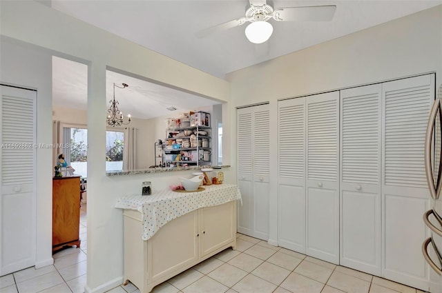 kitchen featuring decorative light fixtures, kitchen peninsula, light stone countertops, light tile patterned floors, and ceiling fan with notable chandelier