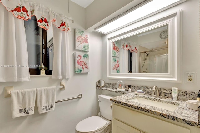 bathroom featuring toilet, vanity, and a shower with shower door