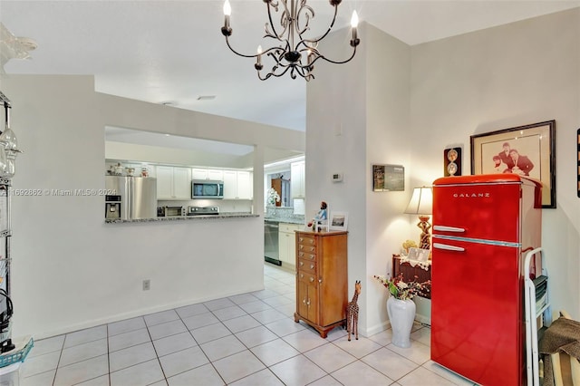 kitchen featuring light tile patterned floors, appliances with stainless steel finishes, a chandelier, and white cabinets