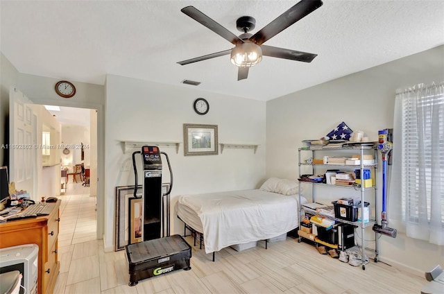 bedroom featuring ceiling fan, a textured ceiling, and multiple windows