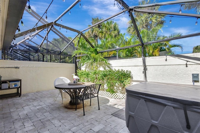 view of patio / terrace with a lanai and a hot tub