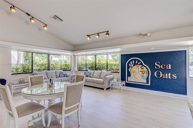 dining space with vaulted ceiling, a healthy amount of sunlight, and hardwood / wood-style floors