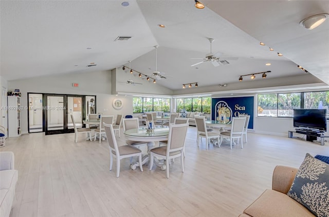 dining space with ceiling fan, light wood-type flooring, and vaulted ceiling