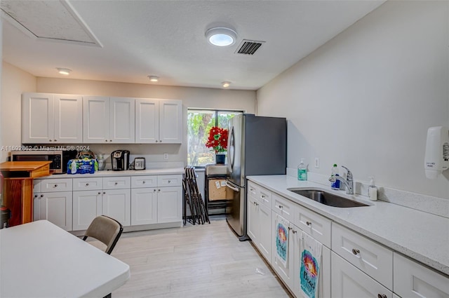 kitchen featuring light stone counters, sink, white cabinetry, and stainless steel appliances