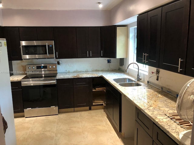 kitchen featuring backsplash, sink, light stone countertops, light tile patterned floors, and stainless steel appliances