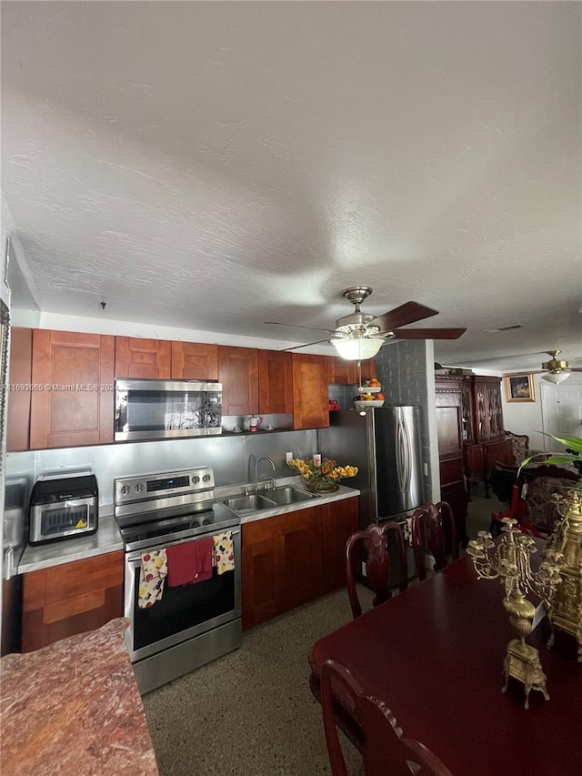 kitchen featuring a textured ceiling, stainless steel appliances, ceiling fan, and sink