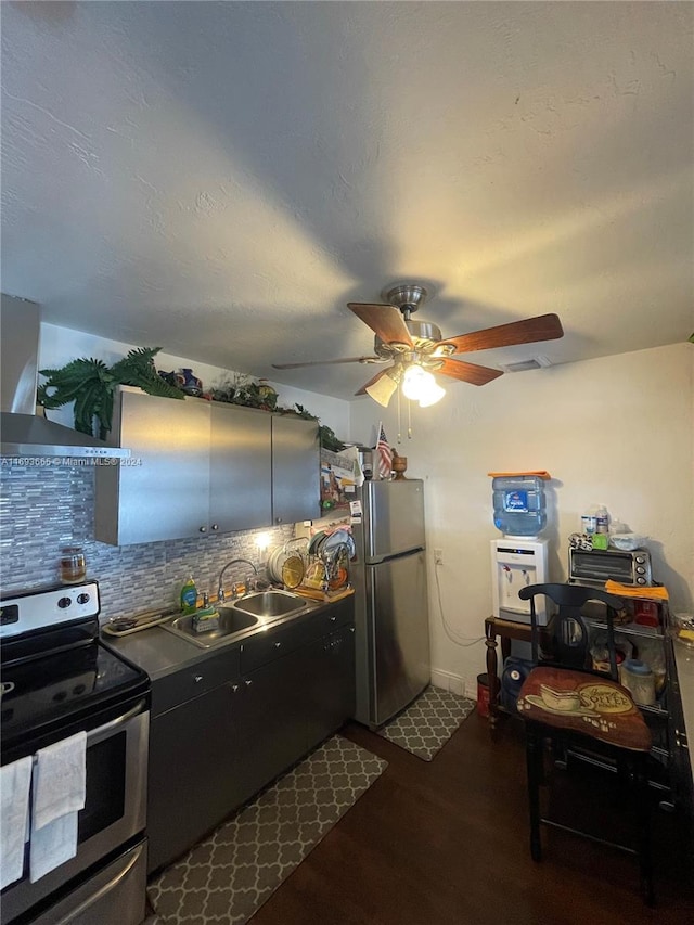 kitchen featuring sink, wall chimney range hood, hardwood / wood-style floors, decorative backsplash, and appliances with stainless steel finishes