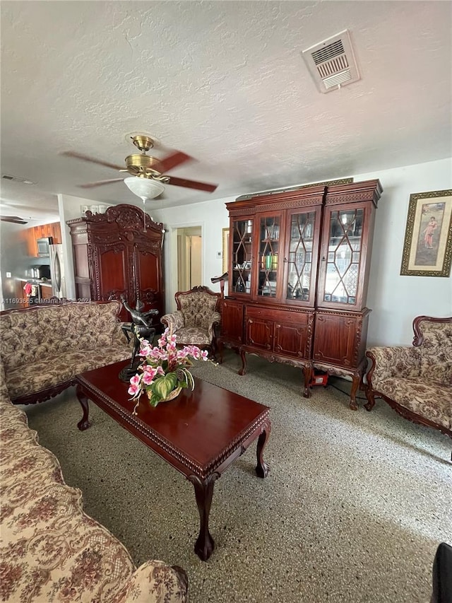 living room featuring ceiling fan and a textured ceiling