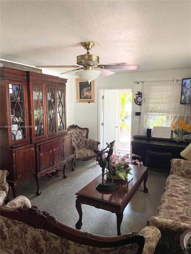 living room featuring ceiling fan and a textured ceiling