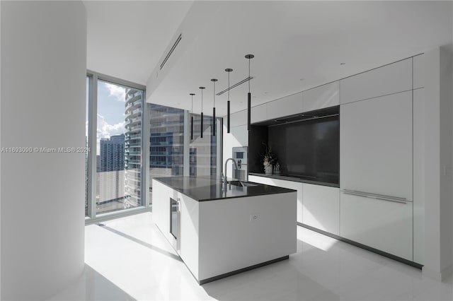 kitchen featuring floor to ceiling windows, a center island, beverage cooler, decorative light fixtures, and white cabinets