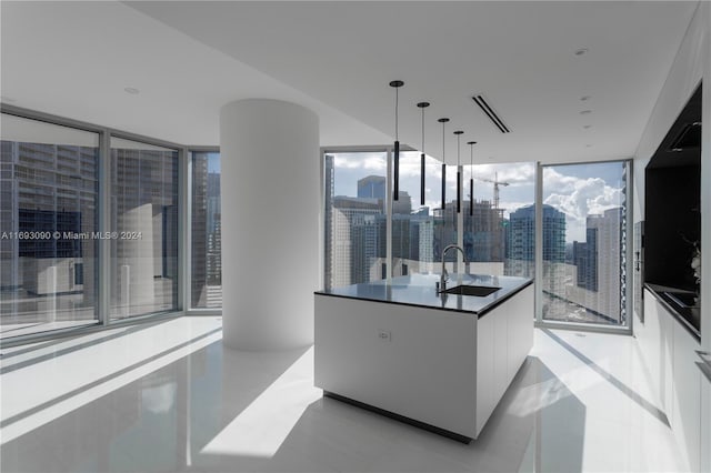 kitchen featuring floor to ceiling windows, sink, white cabinets, and hanging light fixtures