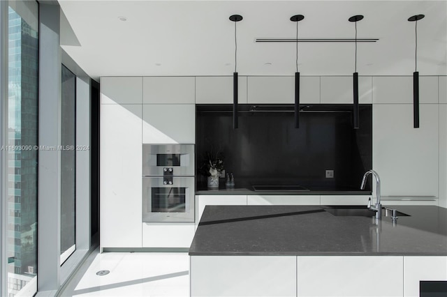 kitchen with sink, hanging light fixtures, black stovetop, white cabinetry, and stainless steel double oven