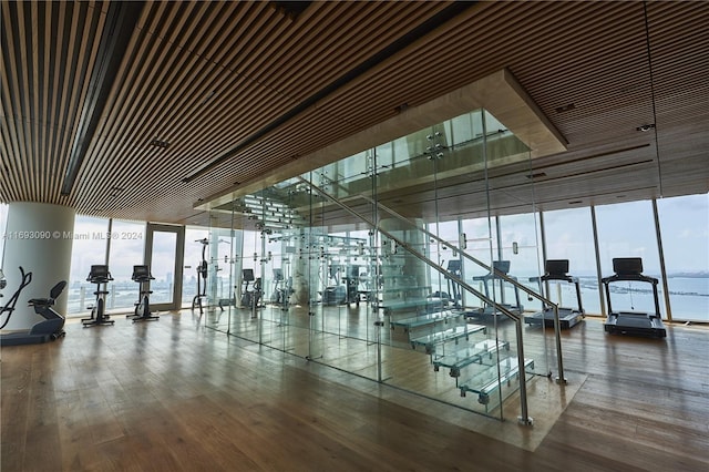 gym featuring hardwood / wood-style flooring and a water view